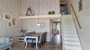 En matplats med ett träbord och stolar, en klocka och en cykel som står på en hylla.