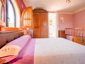 A bedroom with a bed, a wooden wardrobe, a nightstand, and a window with curtains. - Sunny Solarium Holiday Home (Malaga)