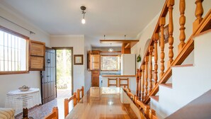 Un hall espacioso con suelo de madera, un comedor con una mesa larga y una escalera con barandilla de madera.