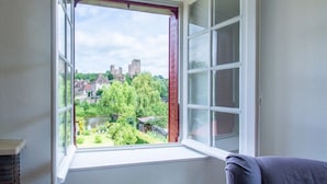 Habitació amb una finestra gran que dona a un edifici històric i un jardí.