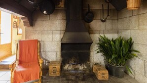 Een rustieke stenen open haard met een houten bank en plantenpotten in de buurt.