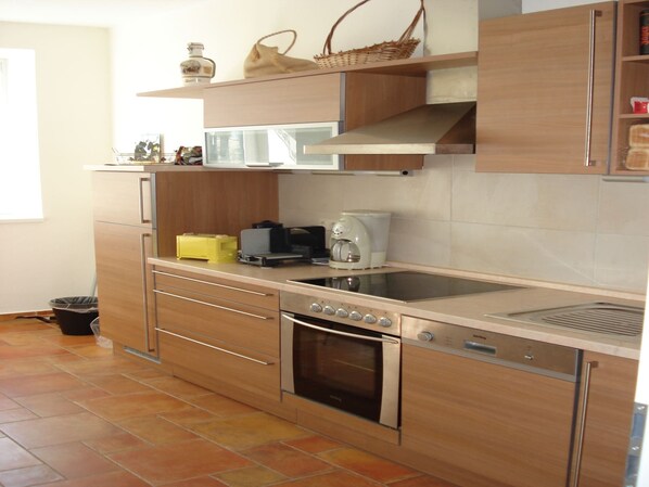 Una cocina moderna con horno empotrado, cafetera y microondas.