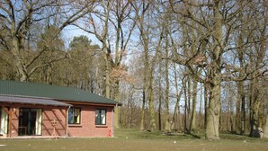 A brick building with a green roof, surrounded by a grassy area and trees.