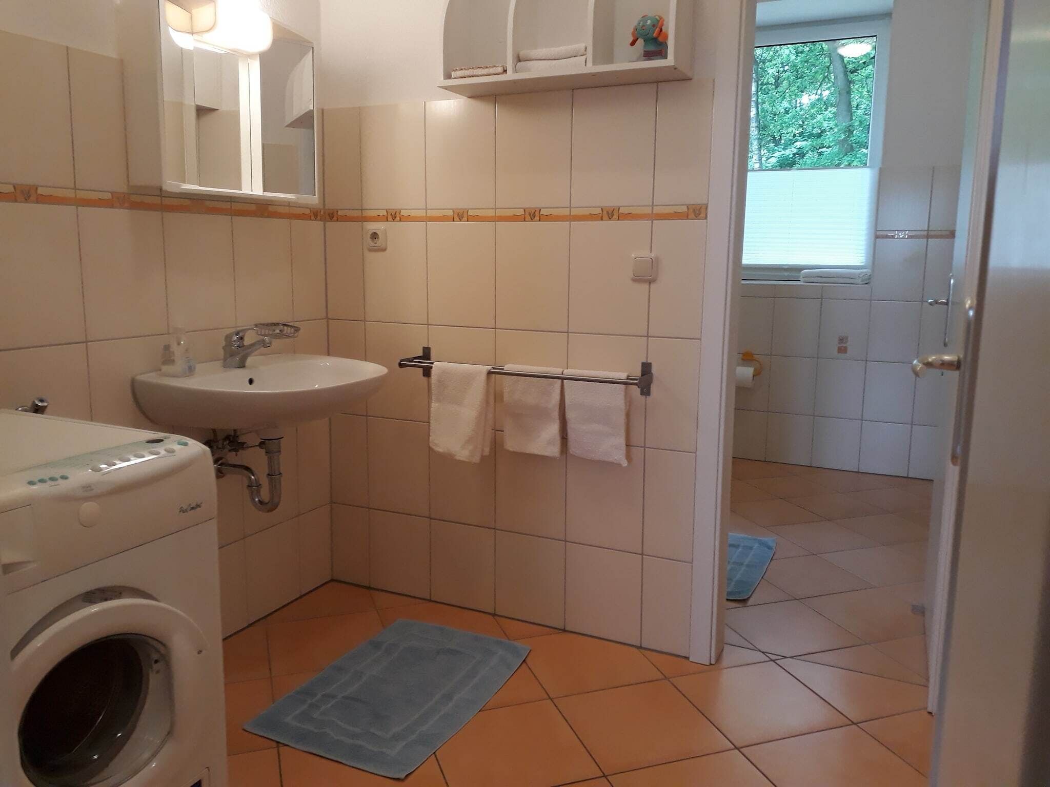 A small bathroom with a sink, a mirror, a towel rack, and a washing machine.