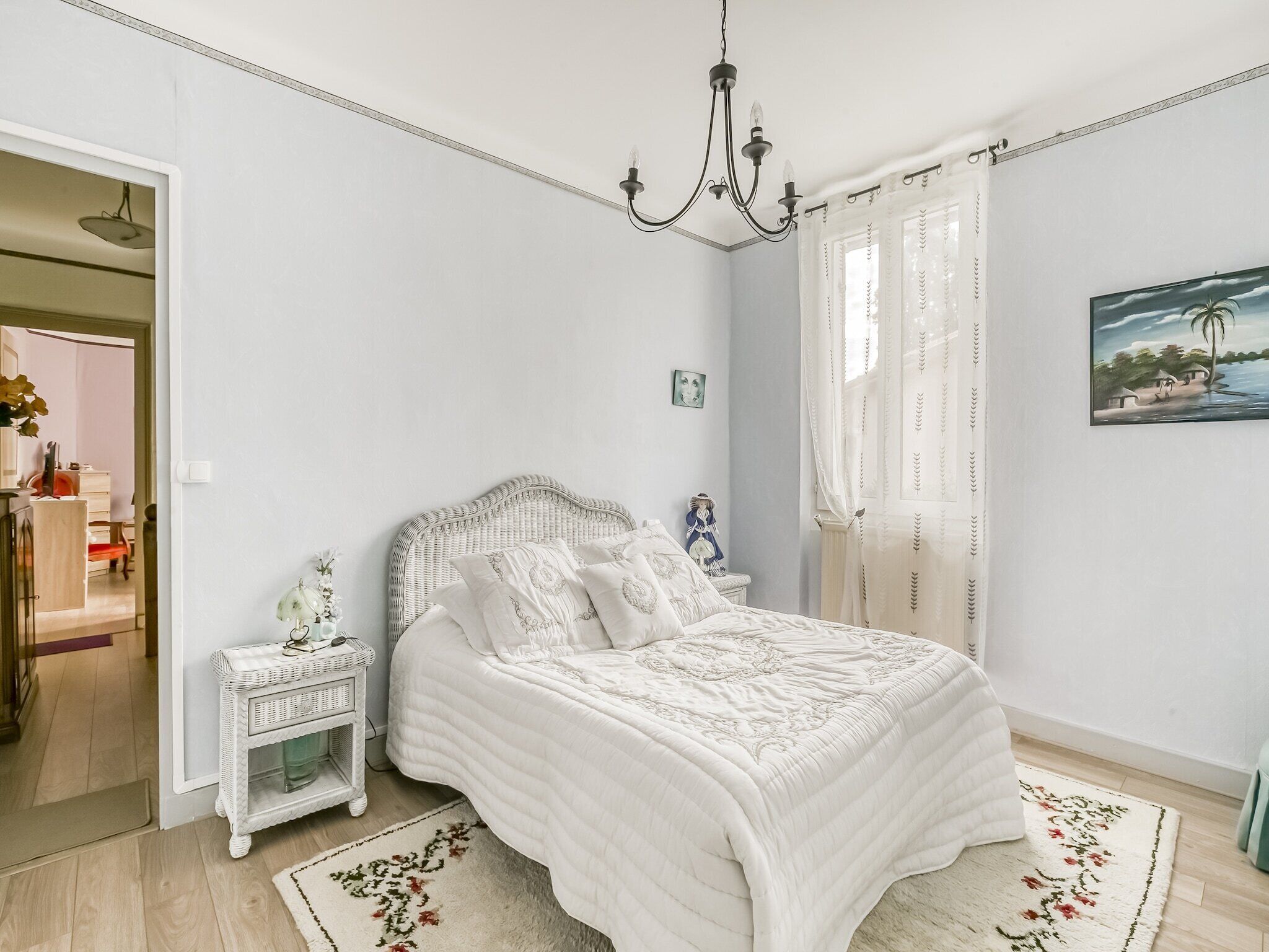 A bedroom with a bed, nightstand, and a painting on the wall.
