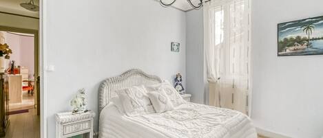 A bedroom with a bed, nightstand, and a painting on the wall.