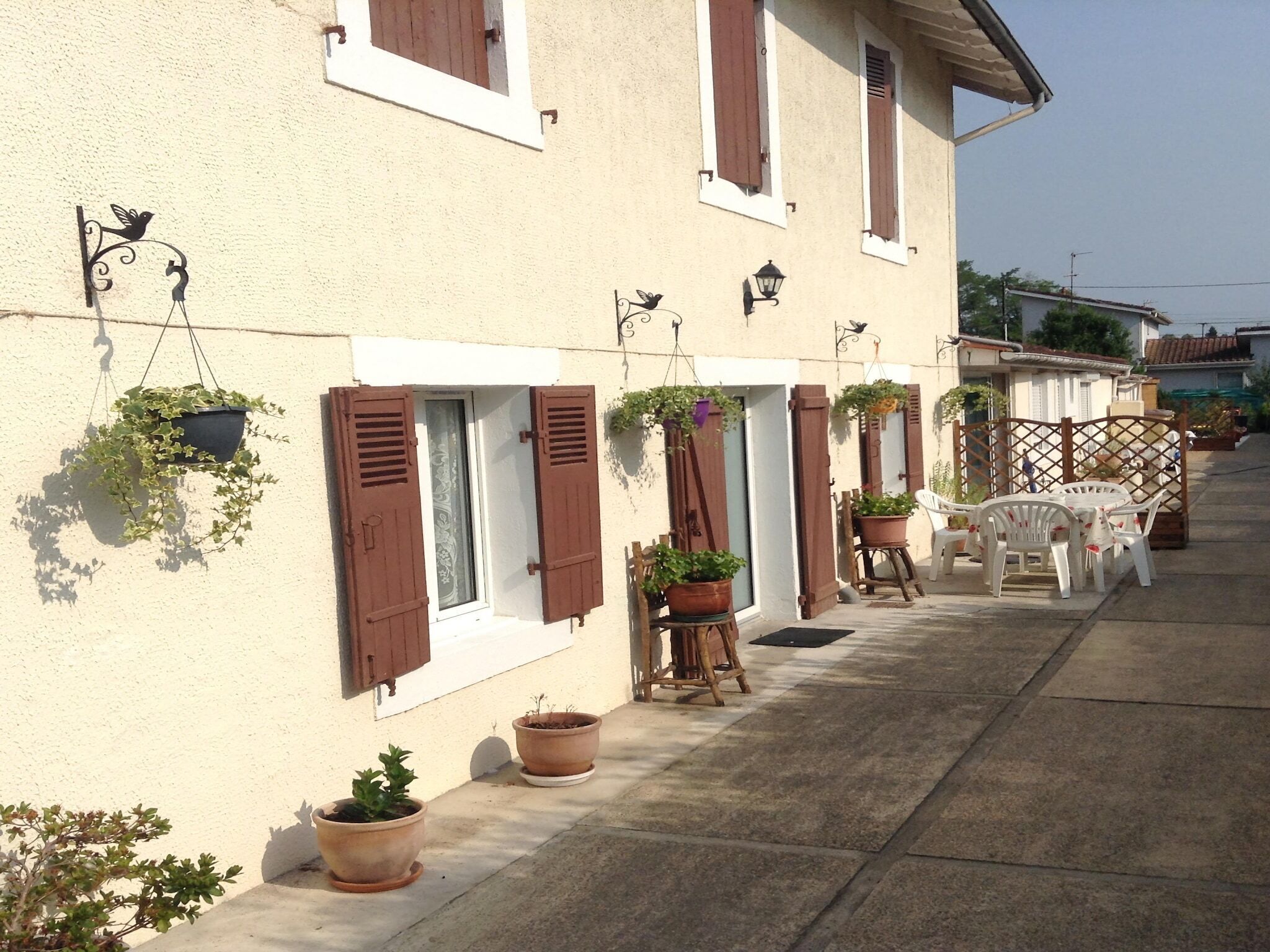 A row of houses with shutters, potted plants, and outdoor furniture.