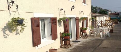 A row of houses with shutters, potted plants, and outdoor furniture.