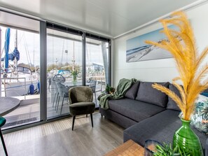 Relax in this stylish living room with a sofa, armchair, and small table, offering a view of the outside area with boats docked.