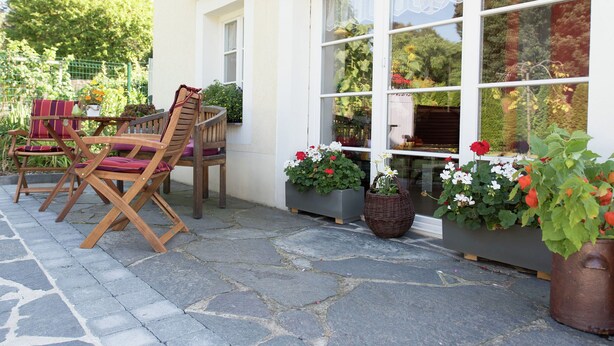 A patio with stone flooring, wooden furniture, and potted plants. - Comfortable holiday home in Saxony with terrace (Oederan)