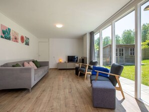 A modern living room with a grey sofa, a blue armchair, and a TV on a white cabinet.