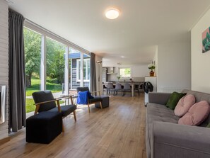 Ein modernes Wohnzimmer mit einer Couch, Sesseln und einem Essbereich.