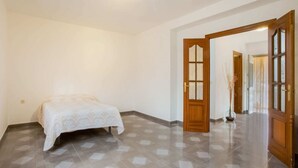 A bedroom with a bed, a wooden door, and a tiled floor. - Casa La Loma with Pool (Andalucía)