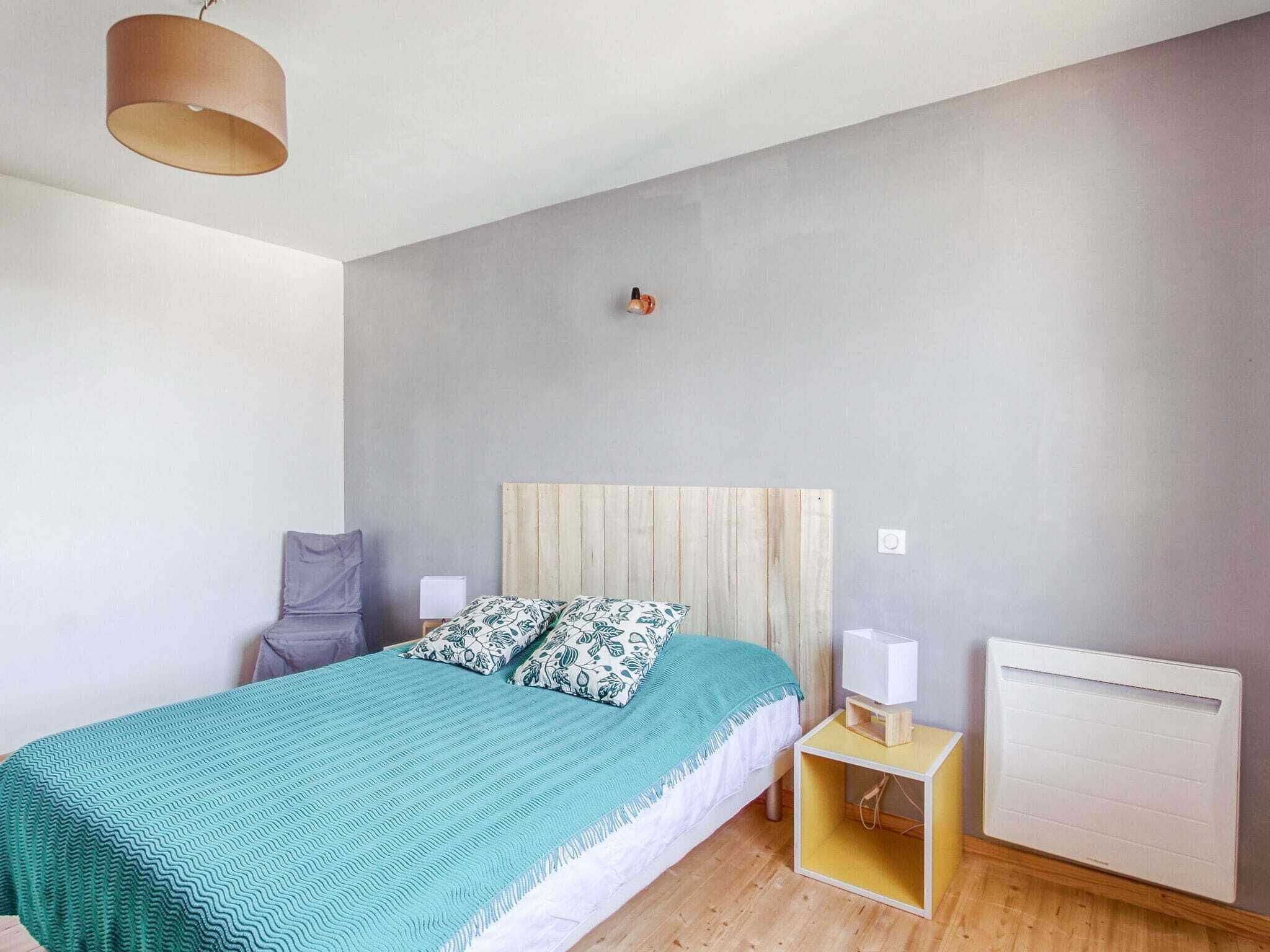 Ein Schlafzimmer mit einem Bett, einem Nachttisch, einer Lampe, einem Heizkörper und einer Deckenleuchte.