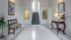 Un pasillo con un banco, una mesa con lámpara, un cuadro enmarcado y una escalera.
