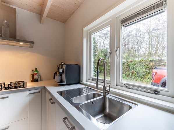 A modern kitchen with two sinks, a coffee machine, and a window overlooking a garden.