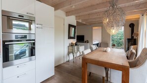 Eine moderne Küche mit eingebauten Backöfen und einem Essbereich mit Holztisch und Stühlen.