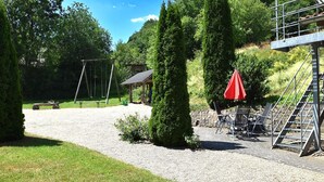 A gravel path leading to a wooden swing set and a gazebo in a park with trees and a metal staircase. - Wohnung in Huddingen mit Terrasse (Bad Wildungen)