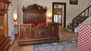 A traditional bedroom with a wooden bed, a red throw pillow, a nightstand, and a lamp. - Outbuilding of a listed 16th-century château (Château-sur-Allier)