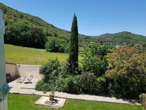 A garden with a seating area, a tall tree, and a view of a bridge in the background. - Villa in La Tour-sur-Orb with Pool & Garden (La Tour-sur-Orb)
