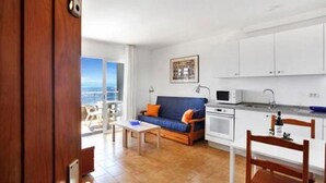 A modern living room with a sofa, coffee table, and a view of the sea.