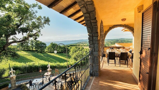 Una terraza con mobiliario exterior, arquitectura de piedra y vistas al campo.