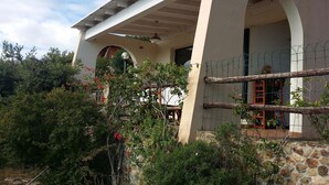 A building with a stone facade, arched windows, and a covered porch area. - Picturesque flat with sea view (Geremeas Quartu Sant'elena)