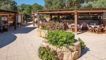 An outdoor patio area with stone planters, wooden tables, and chairs.