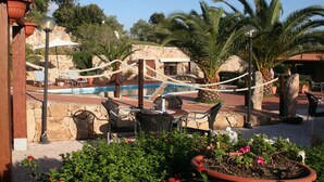 A poolside area with lounge chairs, a pool, and potted plants.