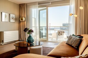 A modern living room with a sofa, a glass coffee table, and a view of a cityscape through large sliding doors. - Modern Apartment in Den Haag (Den Haag)