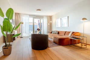 A modern living room with a sofa, ottoman, and a potted plant. - Modern Apartment in Den Haag (Den Haag)
