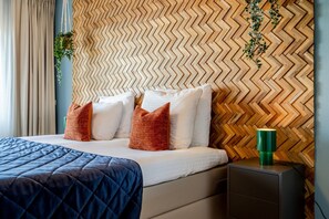 A hotel room with a bed, pillows, a bedside table, and a wall with a herringbone pattern. - Modern Apartment in Den Haag (Den Haag)