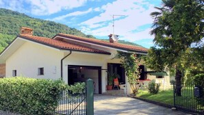 A two-story house with a red-tiled roof, a garage, and a covered outdoor seating area. - Villa in Northern Italy near Borgo di Toppo (Travesio)