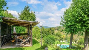 A rustic wooden structure with a bench and a table, surrounded by lush greenery and a clear blue sky. - Holiday Home in Monte Santa Maria with Pool (Monte Santa Maria in Tiberina)