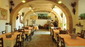 Ein Restaurant mit gewölbter Ziegeldecke, mehreren Tischen mit Stühlen und verschiedenen Blumentöpfen.