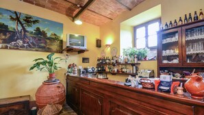 Eine rustikale Bar mit Holztresen, Flaschenregalen und einem an der Wand montierten Fernseher.
