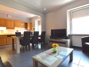 Een moderne woonkamer met een eethoek, een televisie en een salontafel met een kaart.