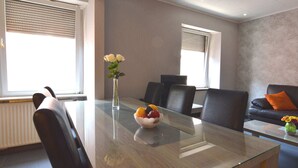 A modern meeting room with a glass table, chairs, a vase with flowers, and a fruit bowl.