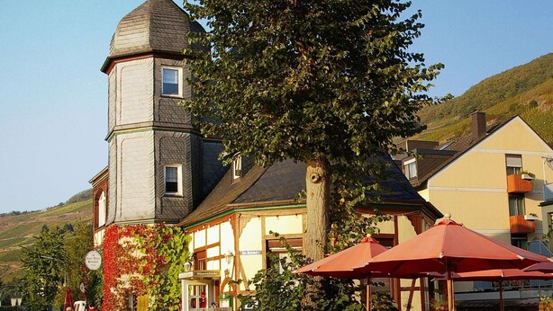 A traditional building with a tower, outdoor seating area, and a signboard.
