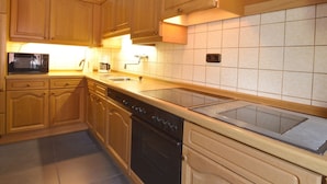 A kitchen with wooden cabinets, a microwave, a coffee maker, and a stove.
