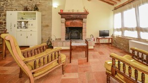 A cozy living room with a fireplace, wooden furniture, and a stone wall. - Holiday Home in Monte Santa Maria with Pool (Monte sta Maria Tiberina)
