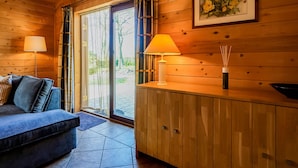 L’intérieur chaleureux d’un chalet, avec un décor en bois, un canapé, une table avec une lampe et un tableau encadré accroché au mur.