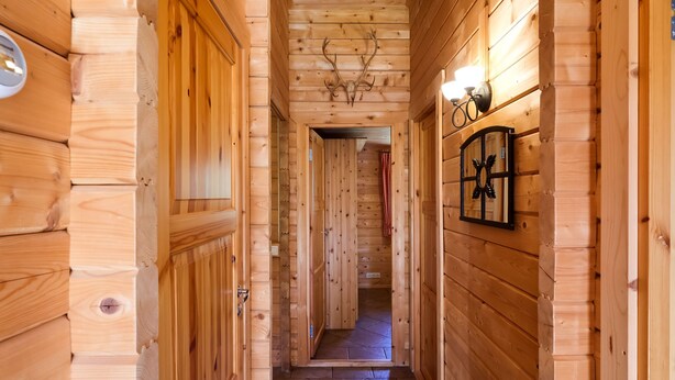 Un couloir en bois, avec un sol carrelé, des murs en bois et un plafond orné de bois de cerf.