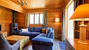 L’intérieur chaleureux d’un chalet avec un plafond en bois, un canapé, une table et une cheminée.