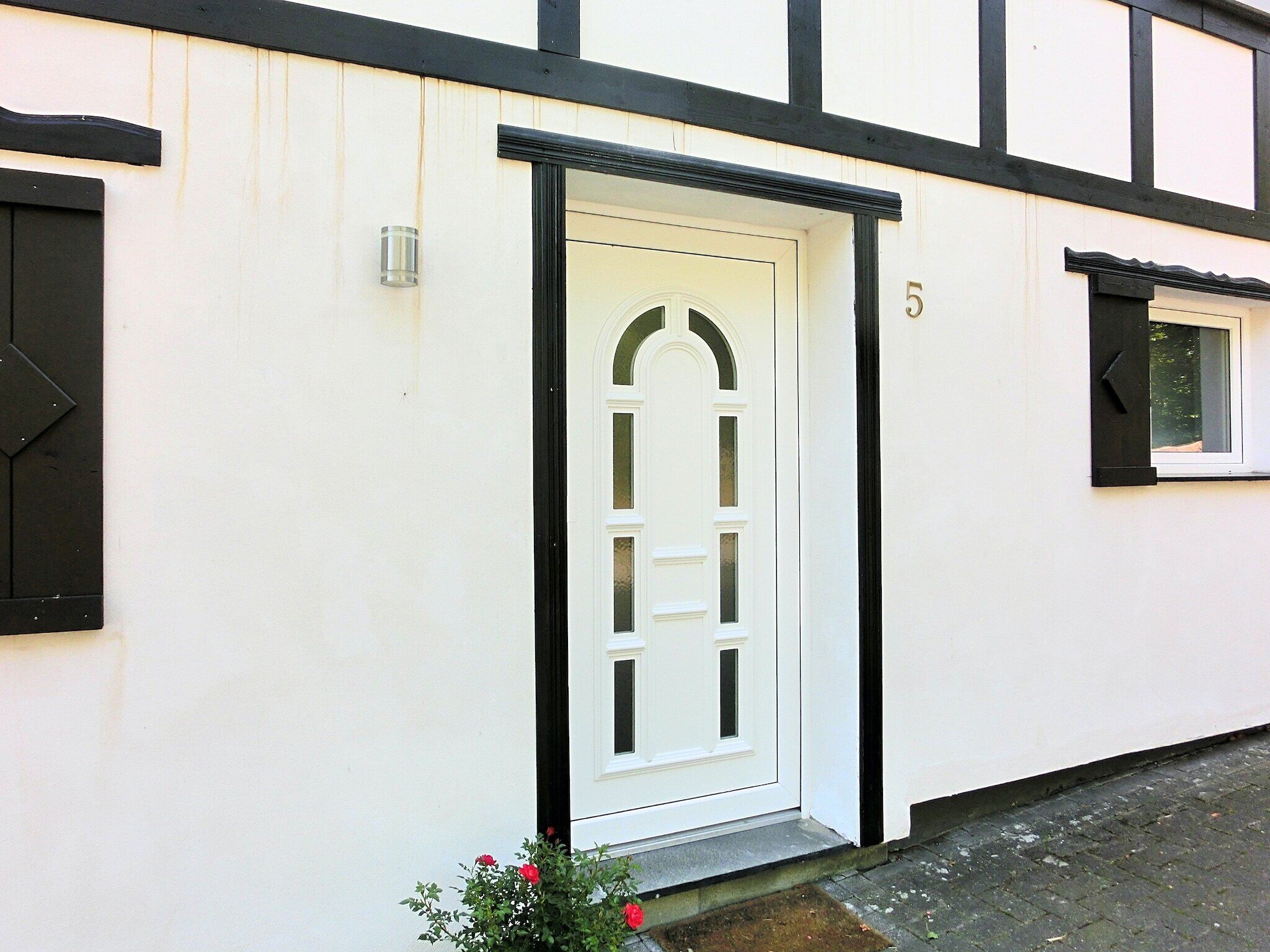 A white building with a black-framed door and window shutters.