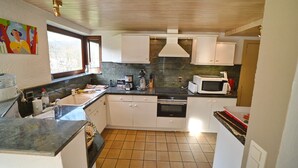 A compact kitchen with white cabinets, a microwave, and a coffee maker. - Lodge in Ardennes near La Roche Center (LA ROCHE EN ARDENNES)