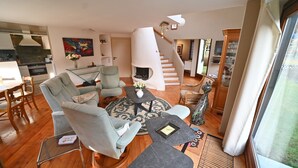 A modern living room with a glass coffee table, two armchairs, a fireplace, and a staircase leading to another level. - Lodge in Ardennes near La Roche Center (LA ROCHE EN ARDENNES)