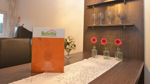 A hotel reception desk with a Belvilla sign, a vase with flowers, and a wine glass display on the wall. - Wohnung nahe dem Skigebiet in Wehrstapel (Meschede)