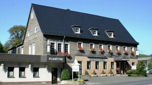 A two-story building with a dark tiled roof and a sign reading "PILSSTUBE" on the ground floor. - Wohnung nahe dem Skigebiet in Wehrstapel (Meschede)