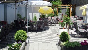 An outdoor café with tables and chairs, a yellow umbrella, and a white tent with text. - Wohnung nahe dem Skigebiet in Wehrstapel (Meschede)
